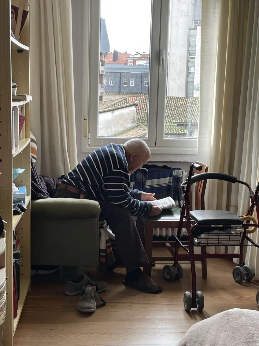 Carmelo at home, reading by the window with his walker
